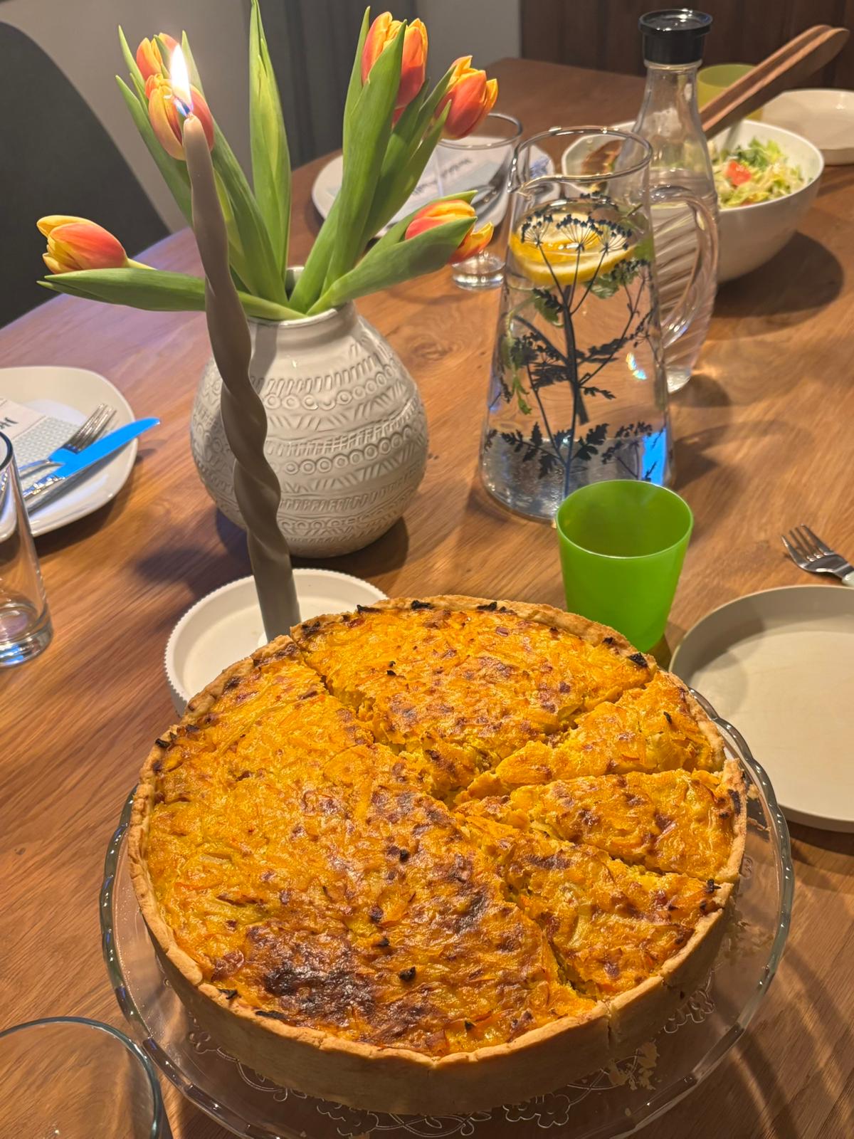 Frisch gebackene Quiche auf einem Tisch mit Tulpen bei einem Running Dinner