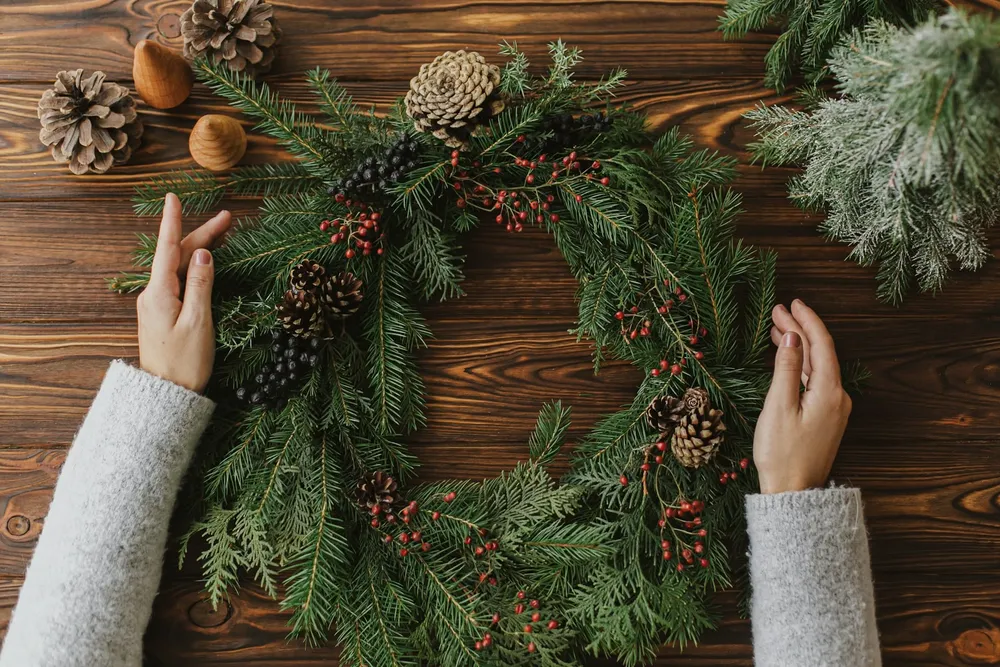 Person bereitet einen Adventskranz vor – Einstimmung auf das Adventsquiz.