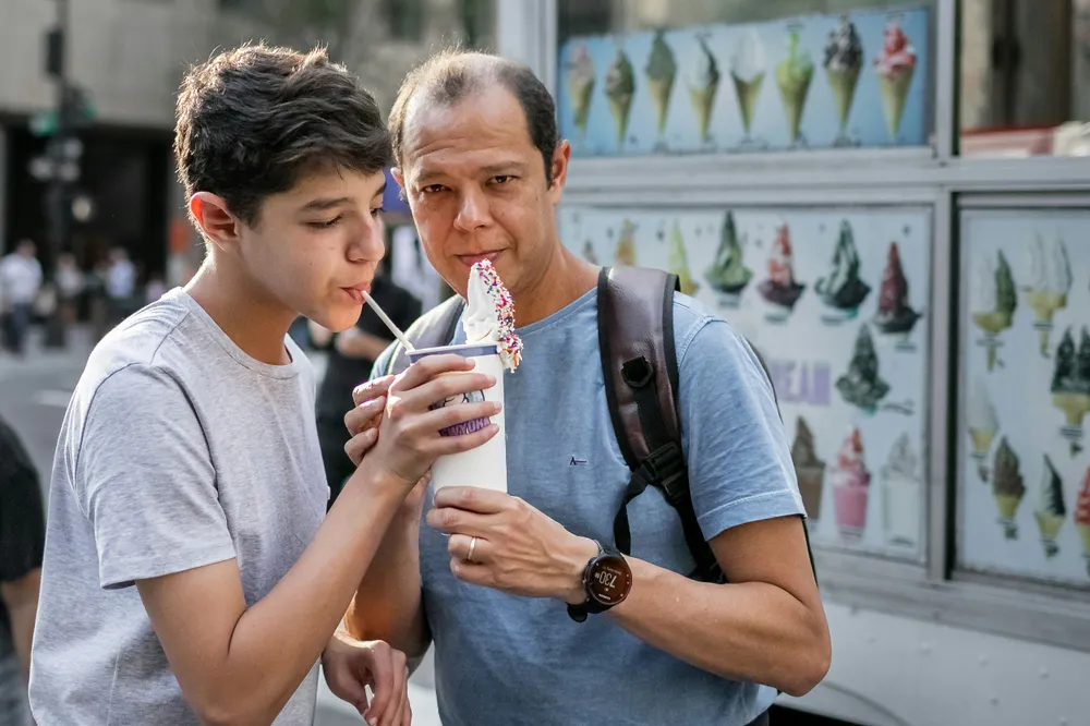 Ein Vater und sein Sohn im Teenageralter teilen sich einen Milchshake.