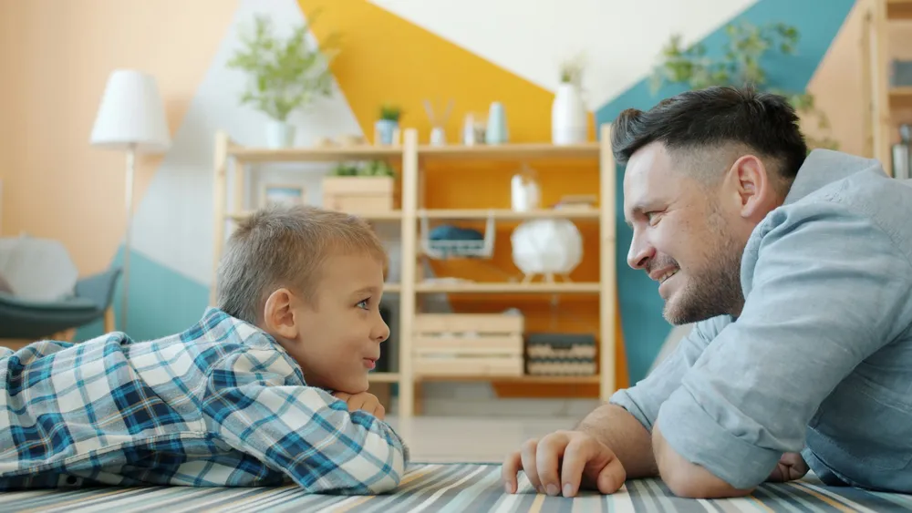 Vater und Sohn liegen auf dem Boden und reden miteinander