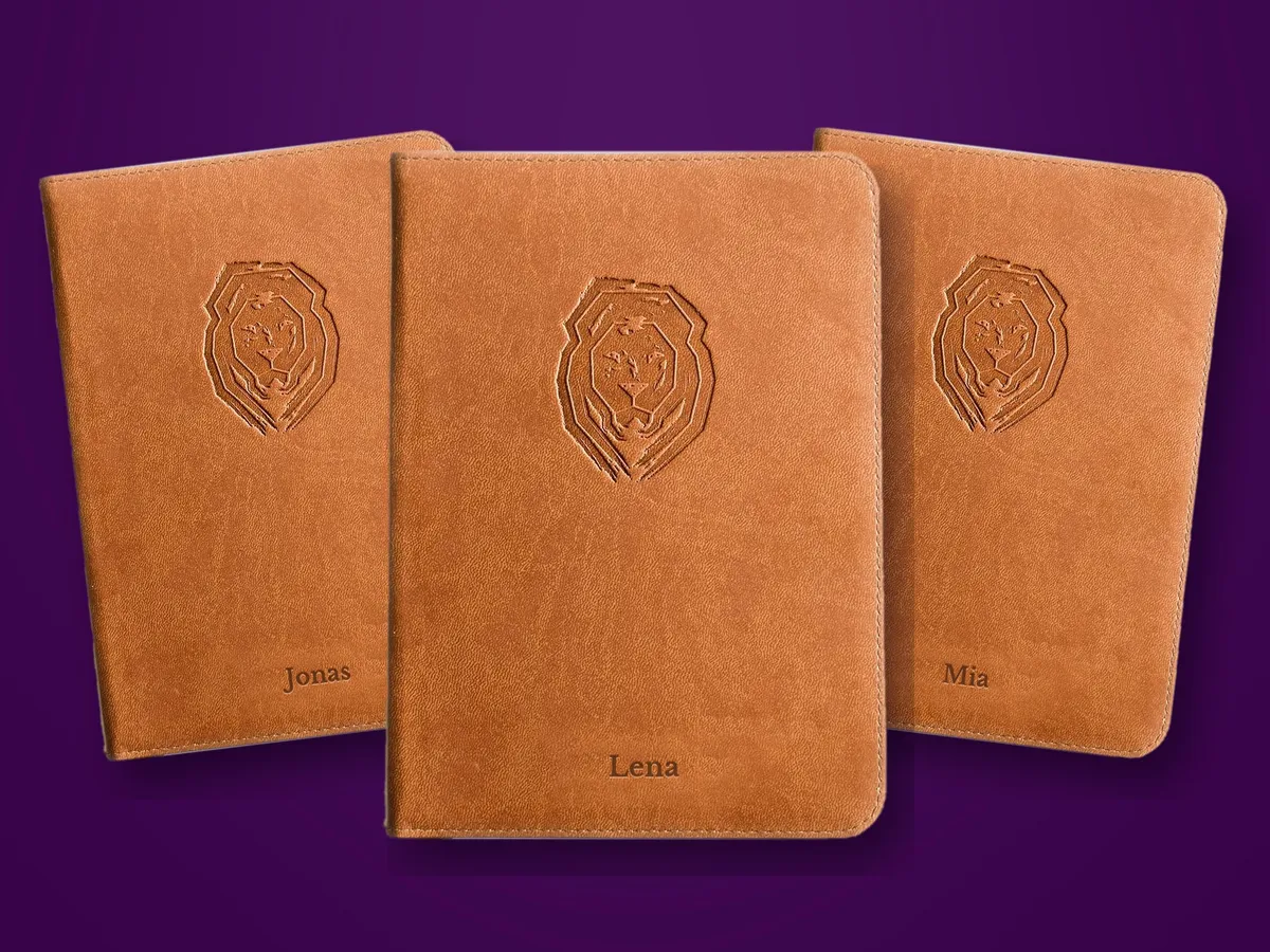 Drei braune Life Lion Bibeln auf violettem Grund, auf den Covern die Namen Lena, Jonas und Mia