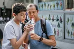 Ein Vater und sein Sohn im Teenageralter teilen sich einen Milchshake.