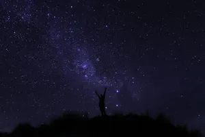 Silhouette unter dem Sternenhimmel mit Milchstraße