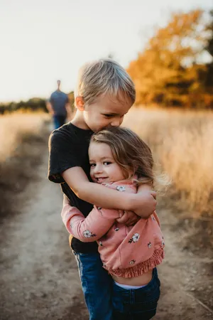 Ein Junge umarmt seine kleine Schwester schützend