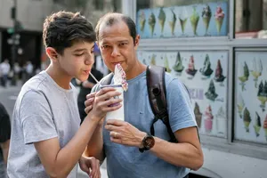 Ein Vater und sein Sohn im Teenageralter teilen sich einen Milchshake.