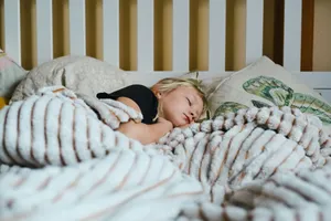 Ein Kind schläft unter einer gestreiften Decke