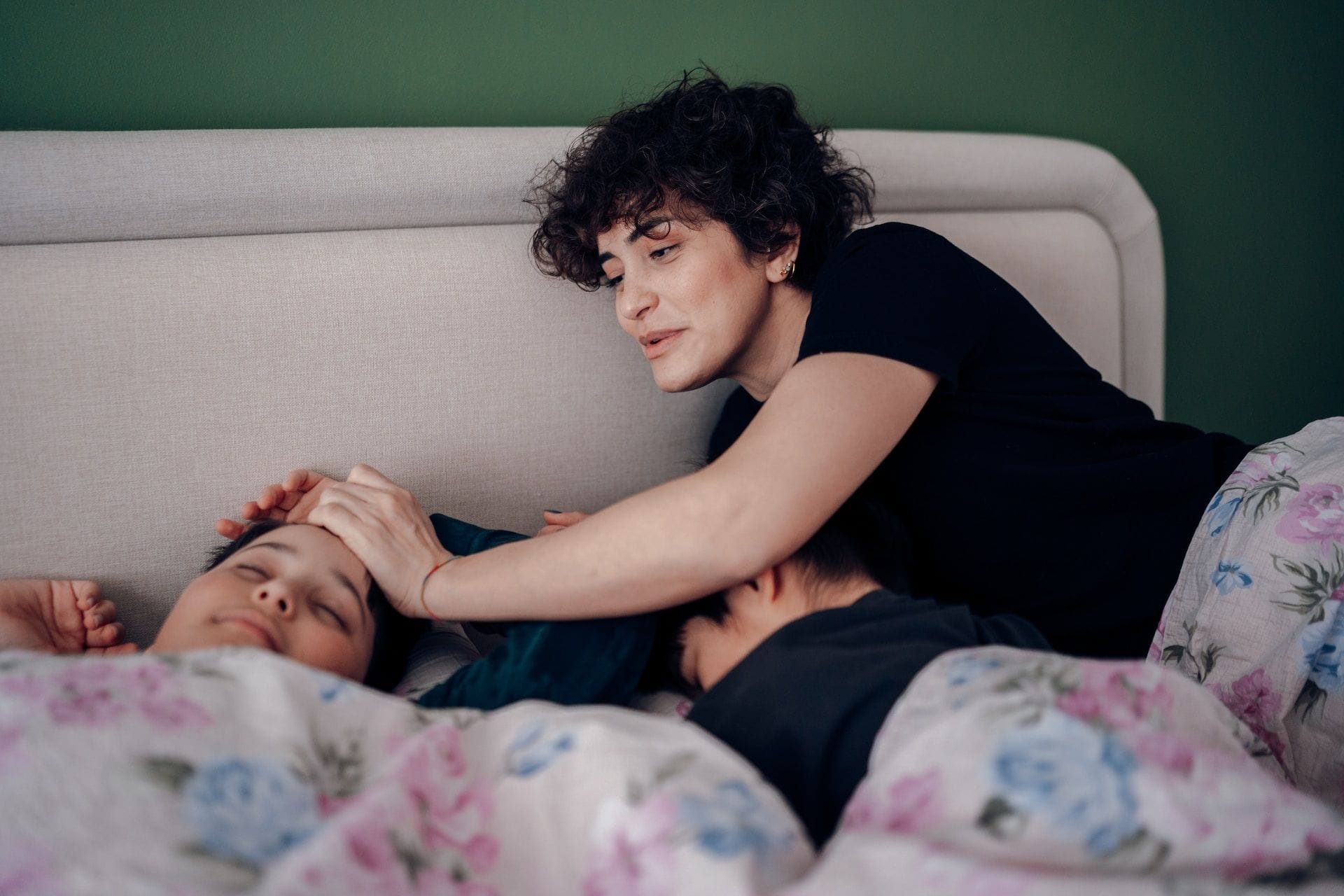 Mother tucking her two sons into bed