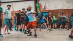 Teenagers in a camp hall playing a ball game; in front, a boy with a headband gets ready to throw