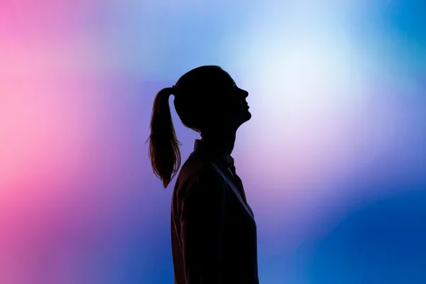Silueta negra de una mujer sobre un fondo violeta, rosa y azul