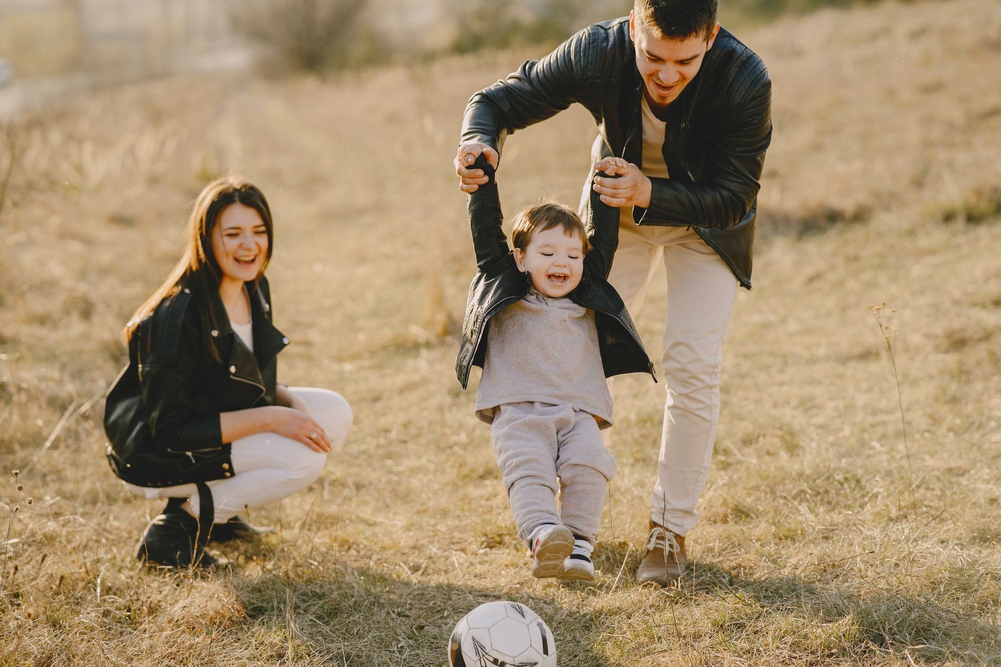 O familie tânără se joacă pe un câmp cu o minge de fotbal