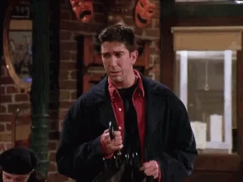 Ross Geller, personajul din serialul Friends, salută stânjenit într-o cafenea, cu o umbrelă închisă în mână
