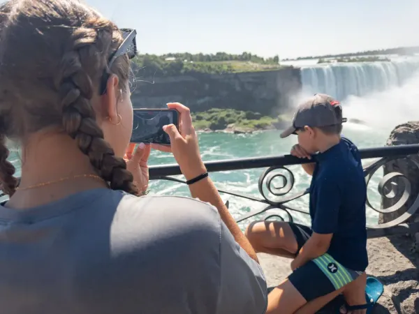 O adolescentă își fotografiază cu telefonul fratele mai mic la Cascada Niagara