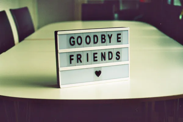 Un panou luminos pe care scrie „Goodbye friends”, cu o inimă, pe o masă de ședințe