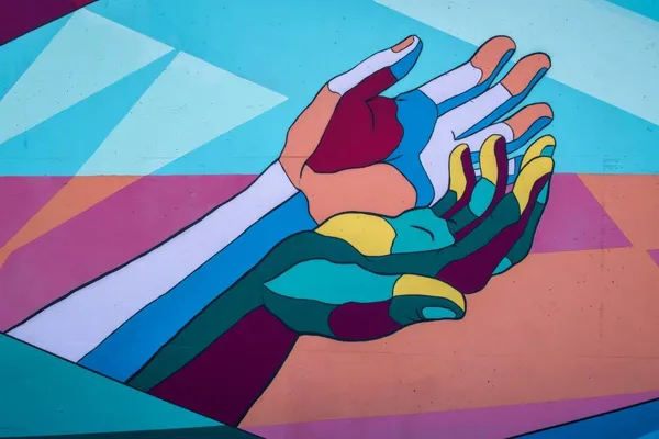 Pictură murală colorată, din forme geometrice: două mâini deschise, una sub alta, cu palmele în sus